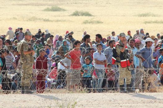 Syrians fleeing the war in their country wait to cross into Turkey