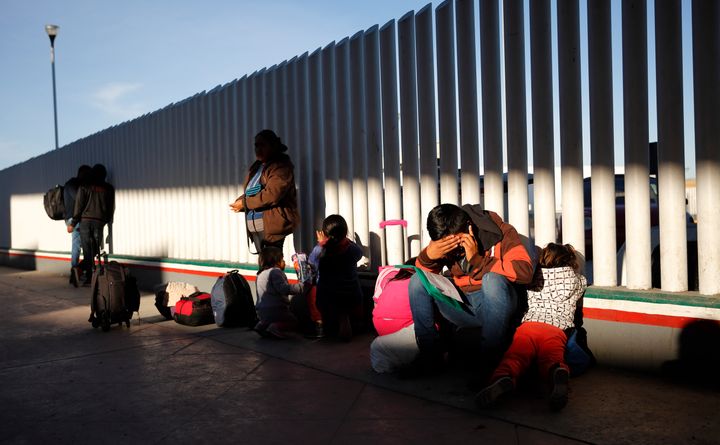 A migrant sits with his children as they wait to hear if their number is called to apply for asylum in the United States, at the border, on Jan. 25, 2019, in Tijuana, Mexico.
