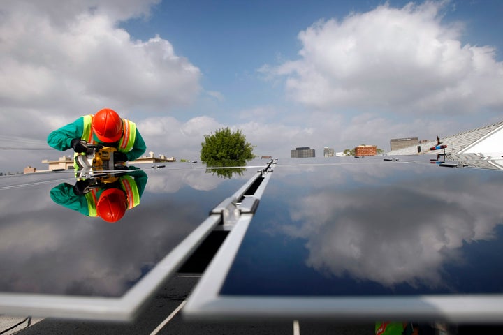 A worker installs a solar panel system on a rooftop in Los Angeles.