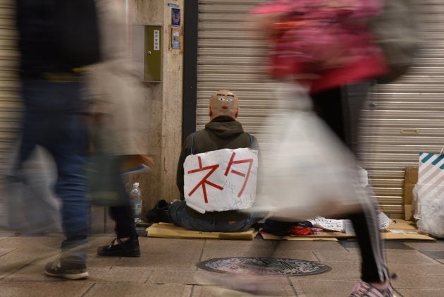 路上に座り、じっと声がかかるのを待つオドゥー＝4月、大阪市中央区