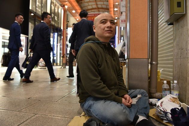 路上に座り、通行人から声がかかるのをじっと待つオドゥー＝4月、大阪市中央区