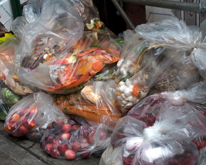 Unsold fresh produce is dumped with the garbage outside a grocery store.