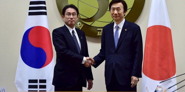 2015年12月28日、慰安婦問題の日韓合意を結んで握手する岸田外相（左）と韓国の尹炳世外相