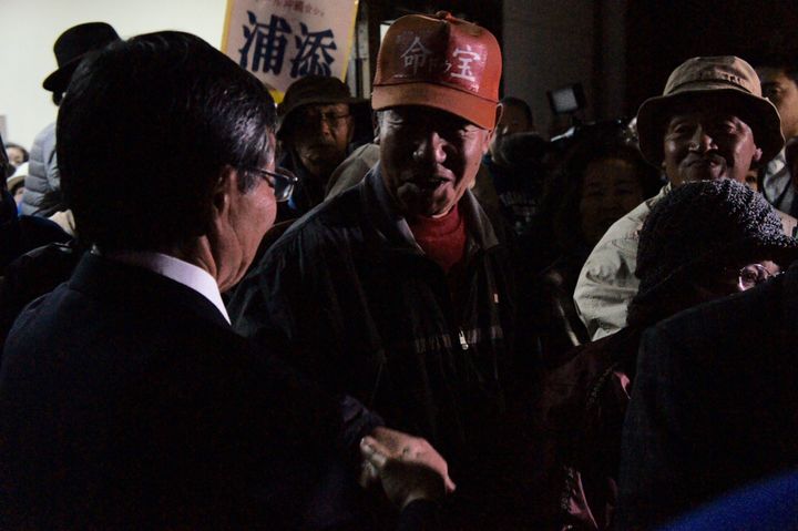 総決起集会後、稲嶺氏（左）と握手して帰る市民（中央）＝1月23日、名護市の21世紀の森屋内運動場