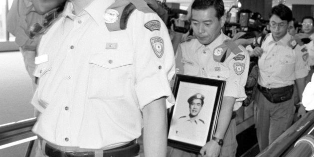 殉職した高田晴行警視の遺影を胸にカンボジアから帰国した文民警察官（千葉・成田空港） 撮影日：1993年07月08日