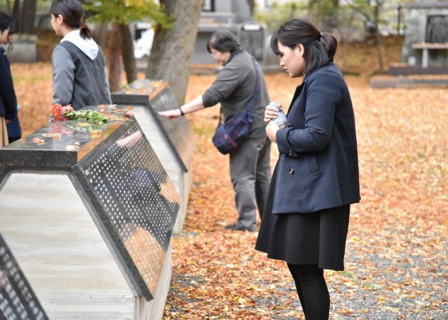 慰霊碑の中から吉岡さんらの名前を探す学生たち