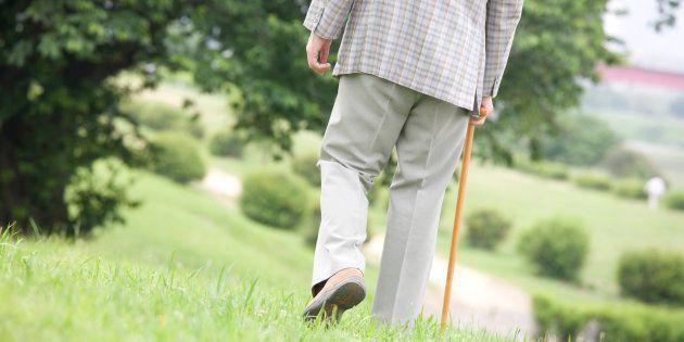 An old man walks with cane Park back
