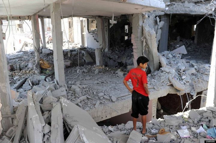 Palestinians inspect the remains of a house which was destroyed during an air strike in Central Bureij refugee camp, in the Middle Area of the Gaza Strip, 15 July 2014 © Shareef Sarhan/UNRWA Archive