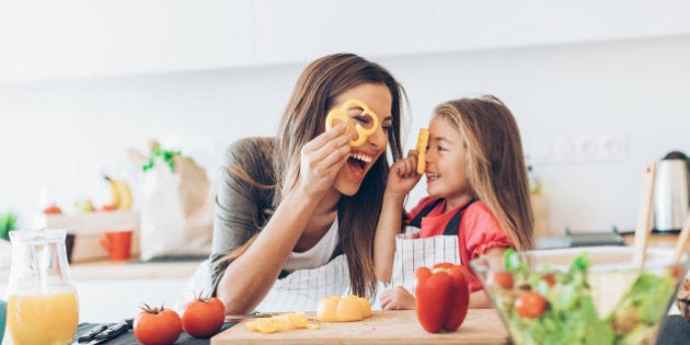 Mother and daughter having fun with the vegetables in the kitchen.