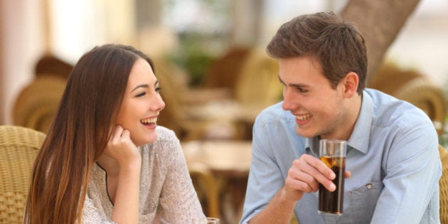 Happy couple or friends talking in a restaurant and looking each other