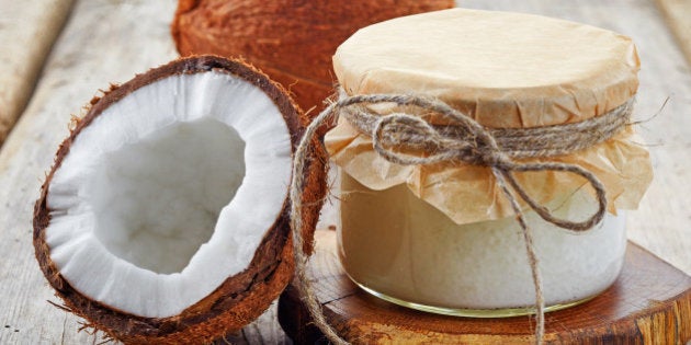 jar of coconut oil and fresh coconuts on wooden table