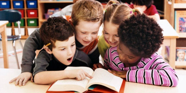 Girls and Boys Looking at the Same Textbook in a Classroom at Primary School