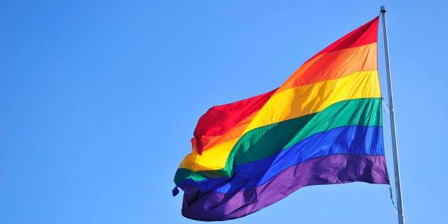 Rainbow flag over blue sky.