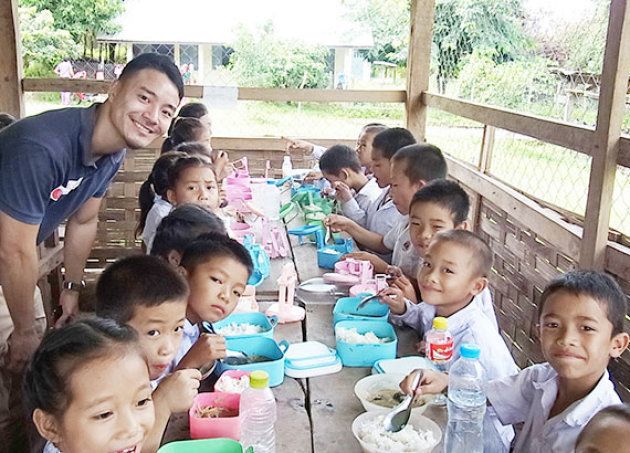給食を食べる児童たちと。左はAARラオス事務所の大城洋作（2017年10月11日）