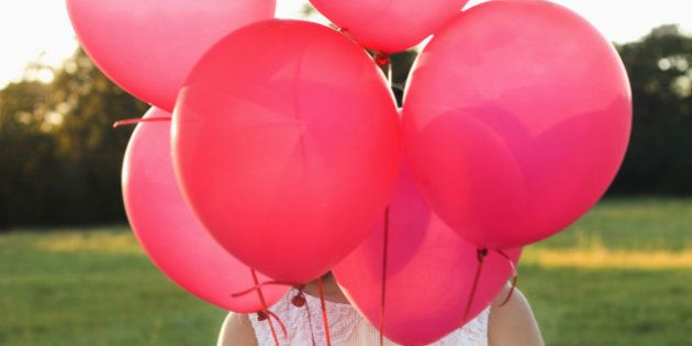 Mixed race woman with pink balloons in park