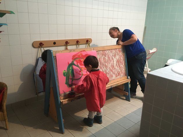 保育場所は保育室に限らない。ここでは浴室横の更衣室を活用。お絵描き台を置き、2歳児2名が保育士1名と水彩をしている。可能な限り少人数でグループ分けをし、保育士・児童ともに集中できる時間を作るという。