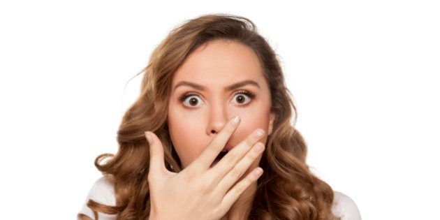 beautiful and shocked young woman holding her hand over her mouth on white background
