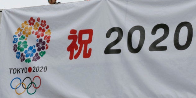 Workers hang a banner celebrating the city's successful bid to host the 2020 Summer Olympics as they prepare for an official event by the Tokyo Municipal Government to report the news to Tokyo citizens at the government office square in Tokyo Sunday morning, Sept. 8, 2013. The International Olympic Committee announced Tokyo as the host city of the 2020 games in Buenos Aires, Argentina. (AP Photo/Shizuo Kambayashi)