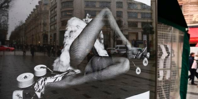 People pass an advertisement for the French luxury fashion brand Yves Saint Laurent on March 6, 2017 on the Champs Elysees in Paris.A new publicity campaign featuring painfully thin models in 'degrading' poses for the French fashion house Yves Saint Laurent sparked outrage March 6, with calls for it to be banned. The poster campaign across Paris of a reclining woman in a fur coat and fishnet tights opening her legs, and another of a model in a leotard and roller skate stilettos bending over a stool, caused fury on social media. / AFP PHOTO / Eric FEFERBERG (Photo credit should read ERIC FEFERBERG/AFP/Getty Images)