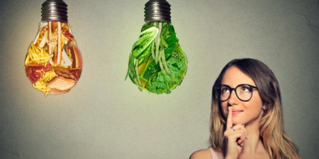 Portrait beautiful woman in glasses thinking looking up at junk food and green vegetables shaped as light bulb isolated on gray background. Diet choice right nutrition healthy lifestyle concept