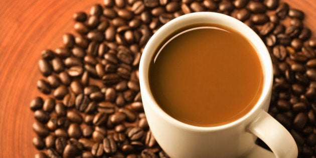 Cup of coffee surrounded by coffee beans