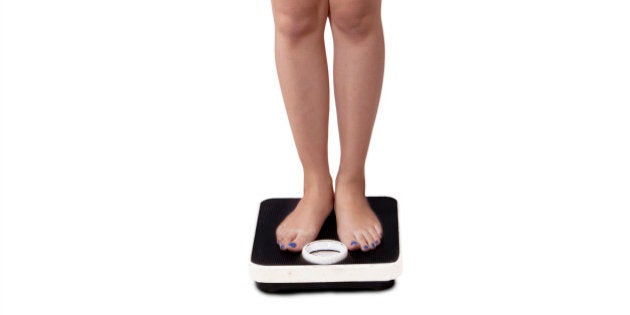 Full length of teenage girl with casual clothes measure her weight with weight scales