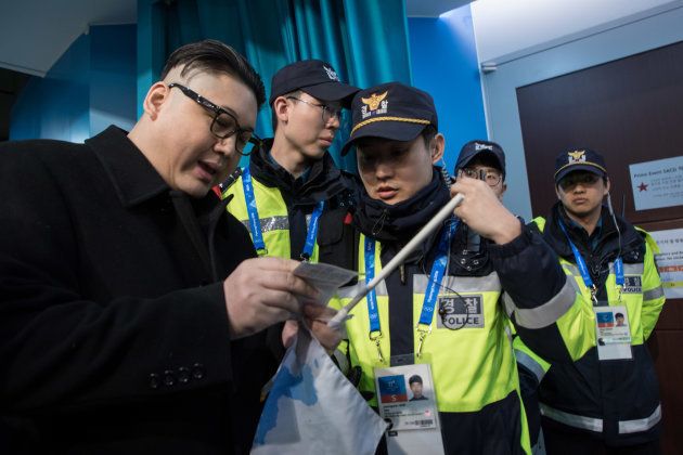 South Korean police check the ticket of a man impersonating North Korean leader Kim Jong Un after he was removed while appearing before North Korean cheerleaders attending the Unified Korean ice hockey game against Japan during the Pyeongchang 2018 Winter Olympic Games at the Kwandong Hockey Centre in Gangneung on February 14, 2018. / AFP PHOTO / YELIM LEE (Photo credit should read YELIM LEE/AFP/Getty Images)