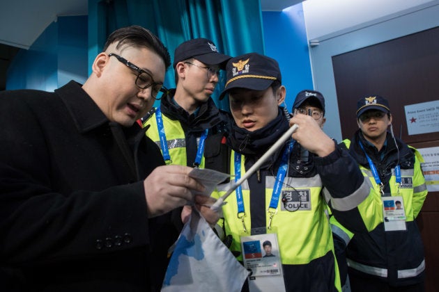 South Korean police check the ticket of a man impersonating North Korean leader Kim Jong Un after he was removed while appearing before North Korean cheerleaders attending the Unified Korean ice hockey game against Japan during the Pyeongchang 2018 Winter Olympic Games at the Kwandong Hockey Centre in Gangneung on February 14, 2018. / AFP PHOTO / YELIM LEE (Photo credit should read YELIM LEE/AFP/Getty Images)