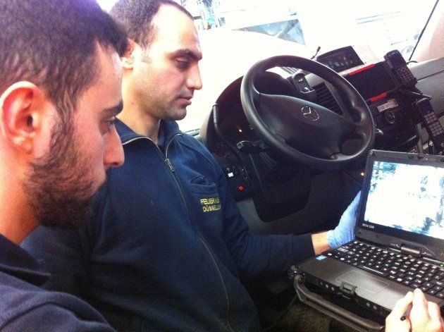 整備工場の職業訓練生、ヘガップさん（左）とアル＝ハムベさん（右）。小型トラックにノートパソコンを接続して、車両の状態をチェックする。
