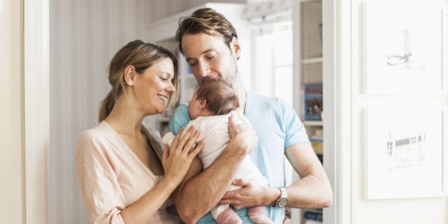 Mid adult coupe playing with baby girl at doorway