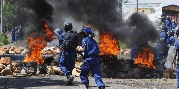 Burundian riot police run past a tire fire during a protest against the president's bid to cling to power for a third term in Musaga, ourskirts of Bujumbura, on April 28, 2015. At least five people have died since clashes broke out on April 26 after the ruling CNDD-FDD party, which has been accused of intimidating opponents, designated President Pierre Nkurunziza its candidate in the June 26 presidential election. On April 28, a spokesman for the President Nkurunziza said the President 'won't back down.' AFP PHOTO / SIMON MAINA (Photo credit should read SIMON MAINA/AFP/Getty Images)
