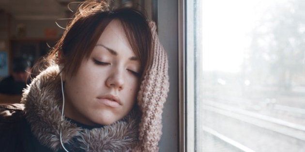 Portrait of sleeping girl, listening to music on headphones. Beautiful brunette in warm clothing