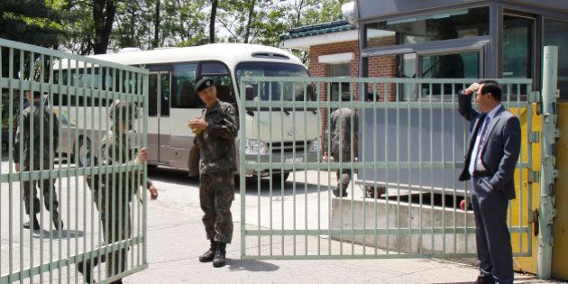 An unidentified relative of a reserve soldier stands in front of a gate of a reserve forces training camp in Seoul, South Korea, Wednesday, May 13, 2015. A South Korean reserve soldier went on a shooting spree Wednesday, killing a fellow reservist and injuring three others before killing himself, army officials said. (AP Photo/Ahn Young-joon)