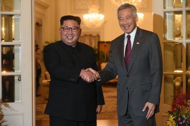 トランプ氏との会談場所であるシンガポールに到着し、同国のリー・シェンロン首相（右）と握手を交わす金正恩氏＝6月10日、シンガポール