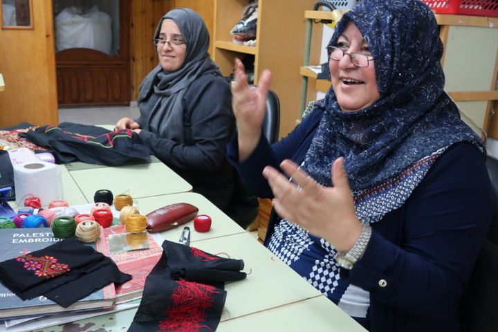 パレスチナ刺繍はアトファルナの人気の職業訓練のひとつ。カバジャ所長の挨拶に手話で応える女性。名刺入れなどの小物からクッションカバーやロングドレスまで、彼女たちの手によって様々な作品が仕上がっていく