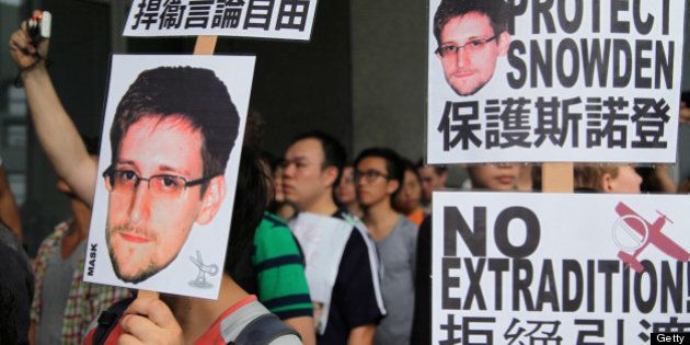 Protesters hold placards outside government headquarters during a rally in support of Edward Snowden, the former National Security Agency contractor, in Hong Kong, China, on Saturday, June 15, 2013. Protesters marched to Hong Kongs government headquarters demanding their leaders protect Edward Snowden, who fled to the city after exposing a U.S. surveillance program. Photographer: Luke Casey/Bloomberg via Getty Images