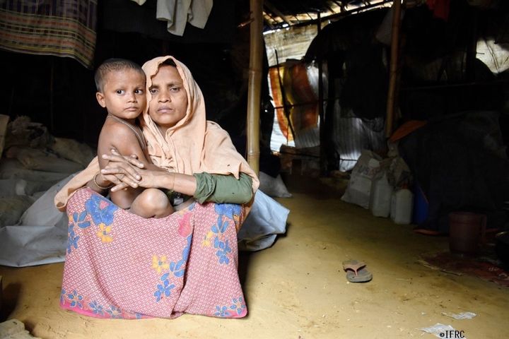 寝泊りするテントのあらゆる方向から入り込む水をバケツで掻き出している住民たち