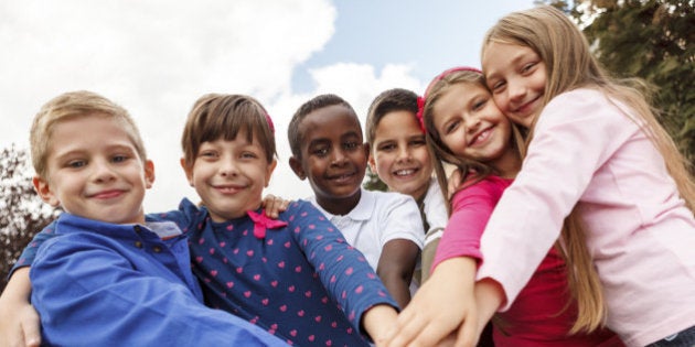 Multiracial school children putting their hands together