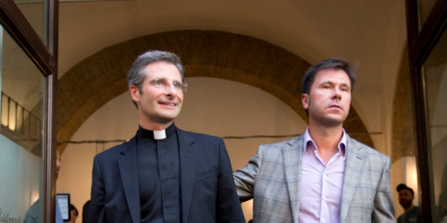 Monsignor Krzysztof Charamsa, left, and his boyfriend Eduard, surname not given, pose for a photo as they leave a restaurant after a news conference in downtown Rome, Saturday Oct. 3, 2015. The Vatican on Saturday fired Charamsa who came out as gay on the eve of a big meeting of the world's bishops to discuss church outreach to gays, divorcees and more traditional Catholic families. (AP Photo/Alessandra Tarantino)