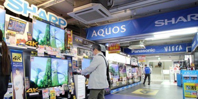 A customer (C) looks at LCD television sets made by Japanese electronics manufacturer Sharp at an electrics shop in Tokyo on May 11, 2015. Sharp lost a quarter of its market value on May 11 following reports that the struggling Japanese electronics giant is planning a drastic capital reduction to help wipe away losses. AFP PHOTO / Yoshikazu TSUNO (Photo credit should read YOSHIKAZU TSUNO/AFP/Getty Images)