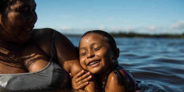 A 4-year-old girl and her mother swim in the Negro river in Manaus, state of Amazonas, Brazil, on November 23, 2013. Manaus will host 4 matches during the FIFA World Cup 2014. AFP PHOTO / YASUYOSHI CHIBA (Photo credit should read YASUYOSHI CHIBA/AFP/Getty Images)