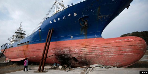A woman looks at a vessel swept inland by the tsunami following the Great East Japan Earthquake in Kesennuma, Miyagi Prefecture, Japan, on Sunday, March 10, 2013. Japan's economy grew at an annualized 0.2 percent last quarter after shrinking 3.7 percent the three previous months, the worst since the 2011 earthquake, revised government data show. Photographer: Kiyoshi Ota/Bloomberg via Getty Images
