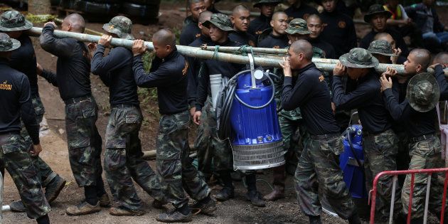 水をくみ出す電動ポンプを運ぶタイの軍関係者ら＝7月6日、タイ北部チェンライ