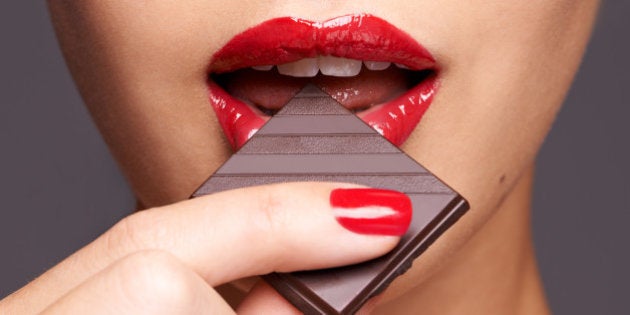 Closeup portrait of a cute young female biting into a piece of chocolate