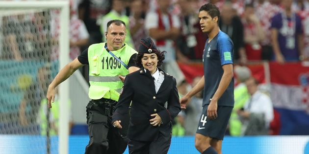 サッカー・ワールドカップの決勝戦に警察官姿で乱入したプッシー・ライオットのメンバー（中央）＝7月15日、モスクワ