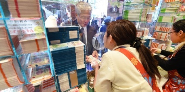 A customer purchases tickets for the 700 million yen (6 million USD) 'Year-end Jumbo Lottery' as the first tickets go on sale in Tokyo on November 21, 2014. Thousands of people queued up for tickets in the hope of becoming a millionaire in the annual lottery. AFP PHOTO/Toru YAMANAKA (Photo credit should read TORU YAMANAKA/AFP/Getty Images)