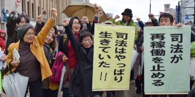 Anti nuclear activists raise their fists in the air to celebrate as the Fukui district court issued a landmark injunction against the restarting of two atomic reactors of Kansai Electric Power Co's Takahama nuclear power plant in Fukui on April 14, 2015, after the country's nuclear watchdog had given the green light to switch them back on. The Fukui district court made the temporary order in response to a bid by local residents to halt the restart of the No. 3 and No. 4 reactors at the Takahama nuclear power plant. AFP PHOTO / JIJI PRESS JAPAN OUT (Photo credit should read JIJI PRESS/AFP/Getty Images)