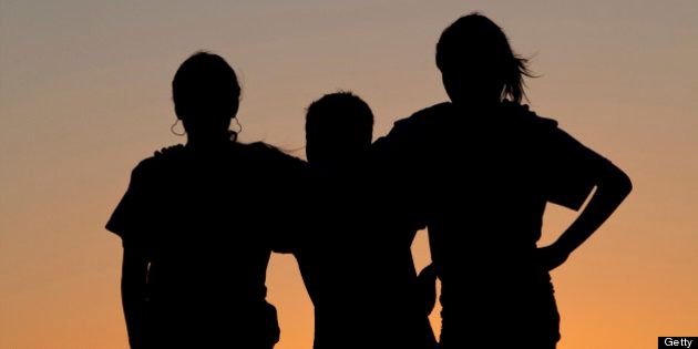 A silhouette of three children bonding at sunset. Affection. Love. Relationships. Friendship.