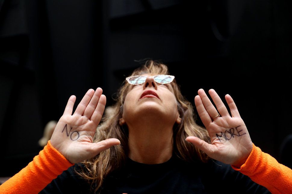 「No More（もう泣き寝入りはしない）」と両手にマジックで書いて抗議の意を表明する女性。