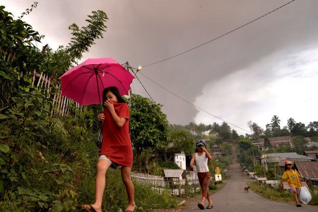 ソプタン山の噴火で灰が降る中、歩く住民ら＝10月3日、スラウェシ島